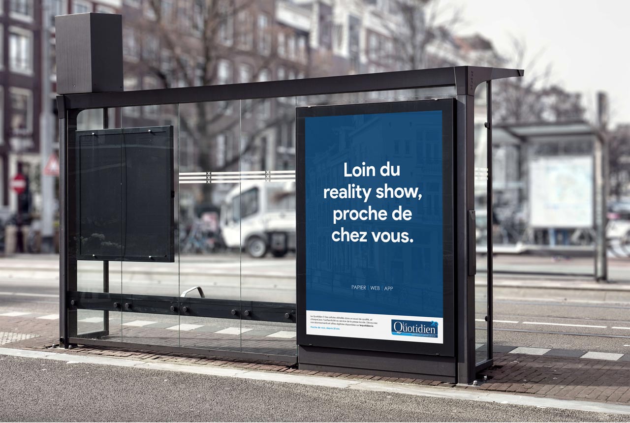 Affichage Decaux dans un arrêt de bus. Le contenu texte de l'affiche : "Loin du reality show, proche de chez vous"